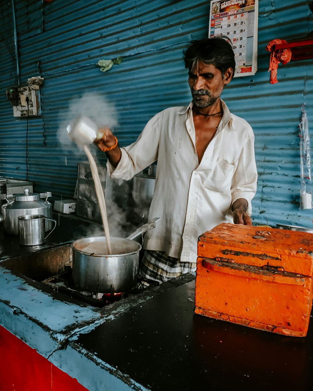Chai Wallah bei der Zubereitung von Chai an einem indischen Straßenstand – echtes Streetfood-Feeling